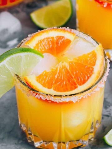 a glass of orange {title:2:3} with orange and lime wedges on the rim