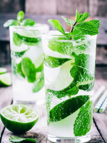 two glasses filled with a {title:2:5} mojito {title:2:1} and mint leaves